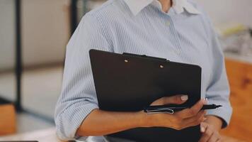 Businesswoman using phone, taking notes at office desk video