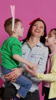 Adorable lovely family showing love and laughing on camera, children feeling happy and playful in studio. Mother with a boy and a girl kissing and hugging each other, joyful people. Camera B. video