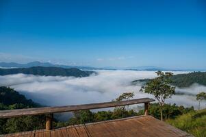 View of forest, mountains and wooden deck with fog in morning at Huai Kub Kab, Chiang mai, Thailand photo