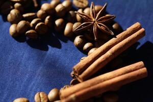 Coffee beans, star anise an cinnamon spices on deep blue background photo