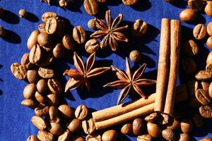 Coffee beans, star anise an cinnamon spices on deep blue background photo