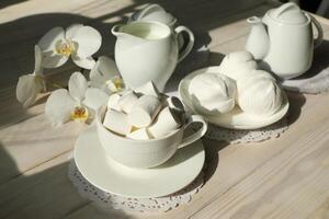 Spring breakfast with marshmallow, coffee and milk. Flatlay with food and flower in white color photo