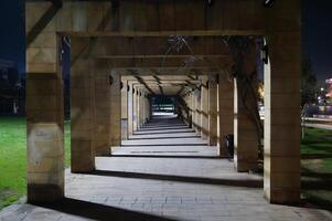 A long, empty walkway with a few lights on photo