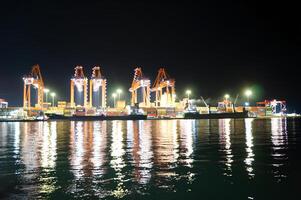 A large group of cranes are lit up at night photo