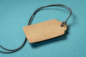 blank paper price tag with a twine against blue textured handmade paper, shopping concept photo