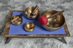 large Tibetan singing bowl with a mallet, roller and wax candle on a low table, sound healing and meditation concept photo