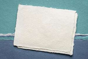 small sheet of blank white Khadi rag paper from India against abstract landscape in blue tones photo