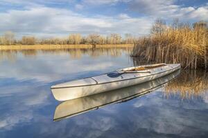 decked expedition canoe on a calm lake in northern Colorado, winter scenery without snow photo