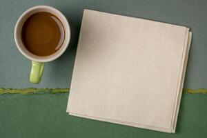 blank napkin with a cup of coffee against abstract green paper landscape photo