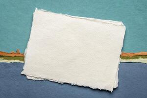 small sheet of blank white Khadi rag paper from India against abstract landscape in blue tones photo