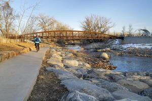 male cyclist is riding a bike in winter sunset scenery - Poudre River Trail in Fort Collins, Colorado at downtown whitewater park, recreation and commuting concept photo