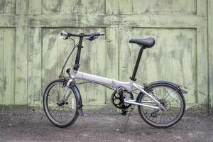 lightweight folding bike in an alley against a grunge wooden fence photo