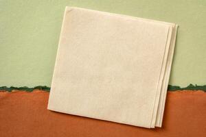 blank napkin against abstract paper landscape in green and orange tones photo