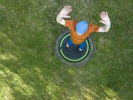 senior overweight male exercising on a mini trampoline in his backyard backyard, fitness and rebounding concept, aerial view photo