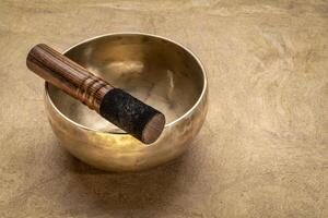 handmade tibetan singing bowl with a mallet on a textured bark paper, sound therapy for healing, relaxation and meditation photo