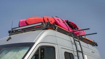 Whitewater kayaks on roof racks of a camper van photo