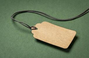 blank paper price tag with a twine against green, textured,  rag paper, shopping concept photo