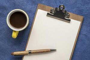 clipboard with a blank paper, desktop flat lay with a cup of coffee and a stylish pen photo