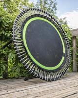 mini trampoline for fitness exercising and rebounding in a backyard patio, summer scenery photo