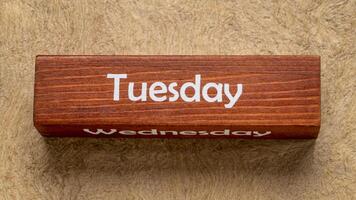 Tuesday and Wednesday text on wooden block against handmade bark paper in earth tones, calendar concept photo
