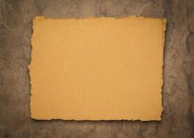 sheet of blank Indian handmade rag paper against textured bark paper, copy space photo