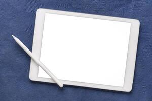 mockup of digital tablet with electronic pencil and a blank isolated screen, clipping path included, against a blue textured art paper photo