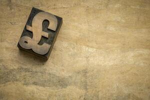 British Pound Sterling symbol in letterpress wood type printing block against bark handmade paper with a copy space photo