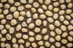 background texture of shelled macadamia nuts on rustic weathered wood - top view photo