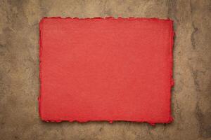 red and brown abstract - a sheet of blank Indian handmade rag paper against textured bark paper, copy space photo