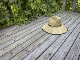 raffia straw sun hat on a rustic wooden backyard deck photo