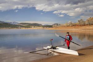 senior rower is rigging his rowing shell on a shore of Carter Lake in northern Colorado in winter scenery photo