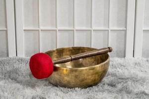 handmade Tibetan singing bowl with a mallet on a fluffy rug, sound therapy for healing, relaxation and meditation photo