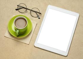 mockup of digital tablet with a blank isolated screen, clipping path included, with a cup of coffee and glasses photo