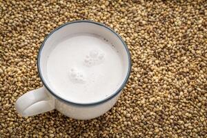 cup of hemp milk against dry hemp seed background photo
