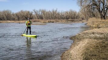 senior male stand up paddler on the South Platte River in Colorado in early spring scenery photo