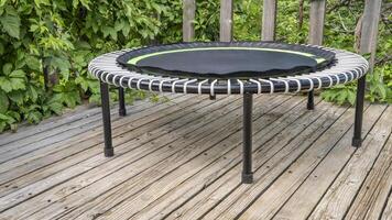 mini trampoline for fitness exercising and rebounding in a backyard patio, summer scenery photo