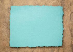 blue and brown abstract, a sheet of blank rag paper against textured bark paper, copy space photo