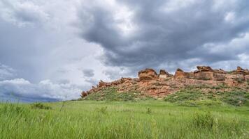 stormy clouds over sandstone cliff and green prairie in Colorado foothills - Lory State Park in late spring scenery photo