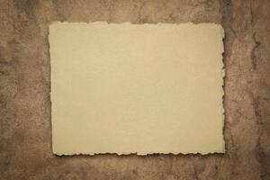 abstract in  earth tone, a sheet of blank Indian handmade rag paper against textured bark paper, copy space photo