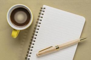 blank spiral sketchbook against textured paper with a cup of coffee, desktop flat lay photo