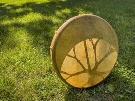 handmade, native American style, shaman frame drum on a grass backlit by sun photo