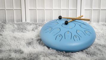 blue steel tongue drum on a fluffy rug photo