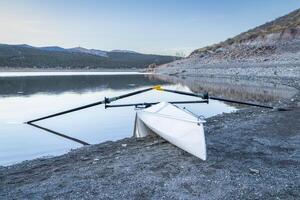 Coastal rowing shell on a shore of Carter Lake in northern Colorado at dusk in winter scenery photo