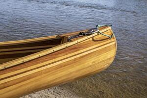 a bow of beautiful, home built, wooden canoe on a river shore photo