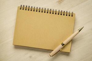 blank spiral notebook with a luxury pen against wooden background photo