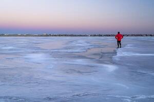 lonely male figure on a frozen lake at dusk in Colorado - Boyd Lake State Park photo