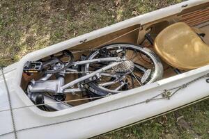 folding bike packed into a cockpit of expedition canoe photo