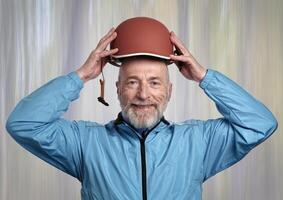 portrait of a senior make cyclist in late 60s wearing a new bright blue biking jacket and holding a helmet photo