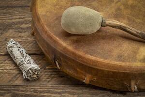 handmade, native American style, shaman frame drum covered by goat skin with a beater and sage incense bundle photo