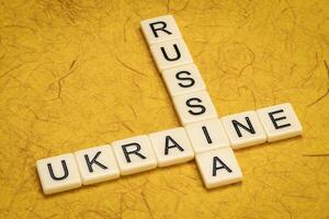 Ukraine and Russia crossword in ivory letter tiles against textured handmade paper photo